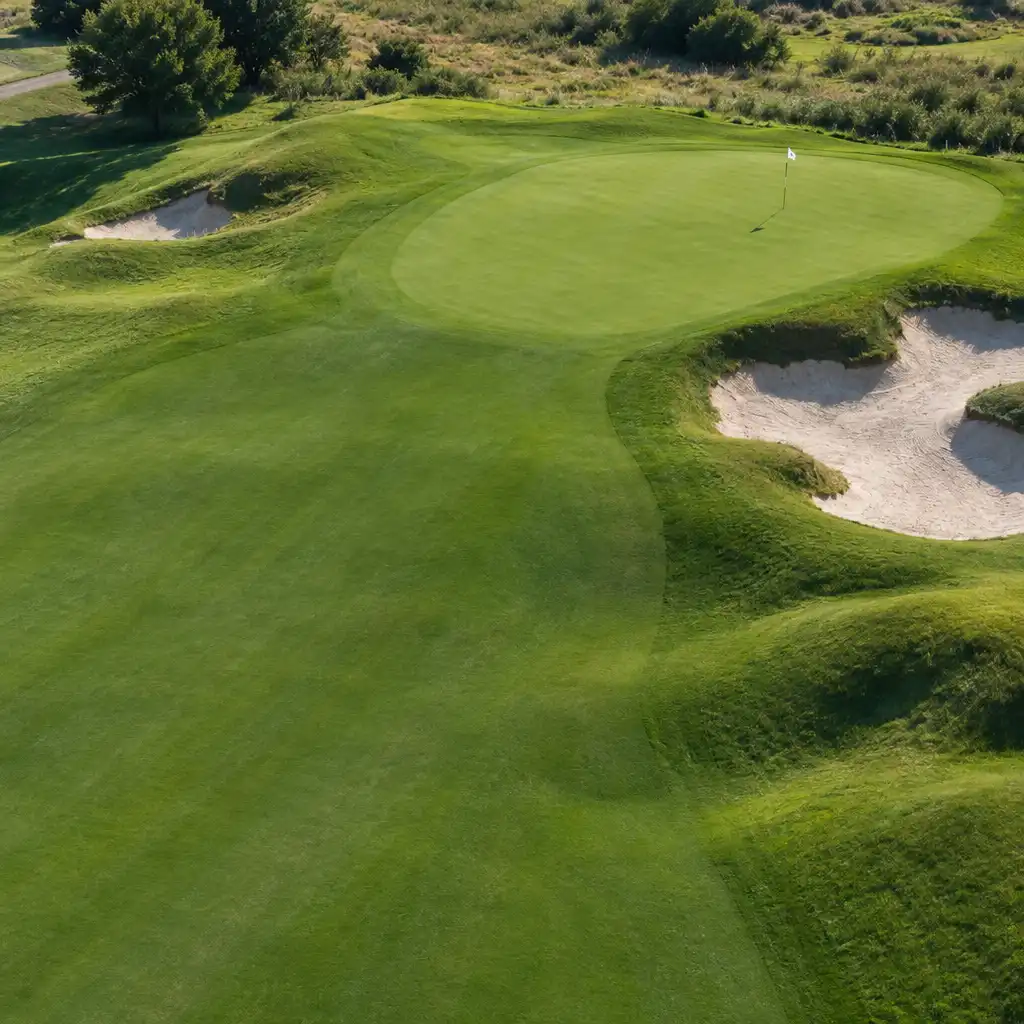 Vue aérienne oblique d’un green entouré d’un fairway et d’un bunker